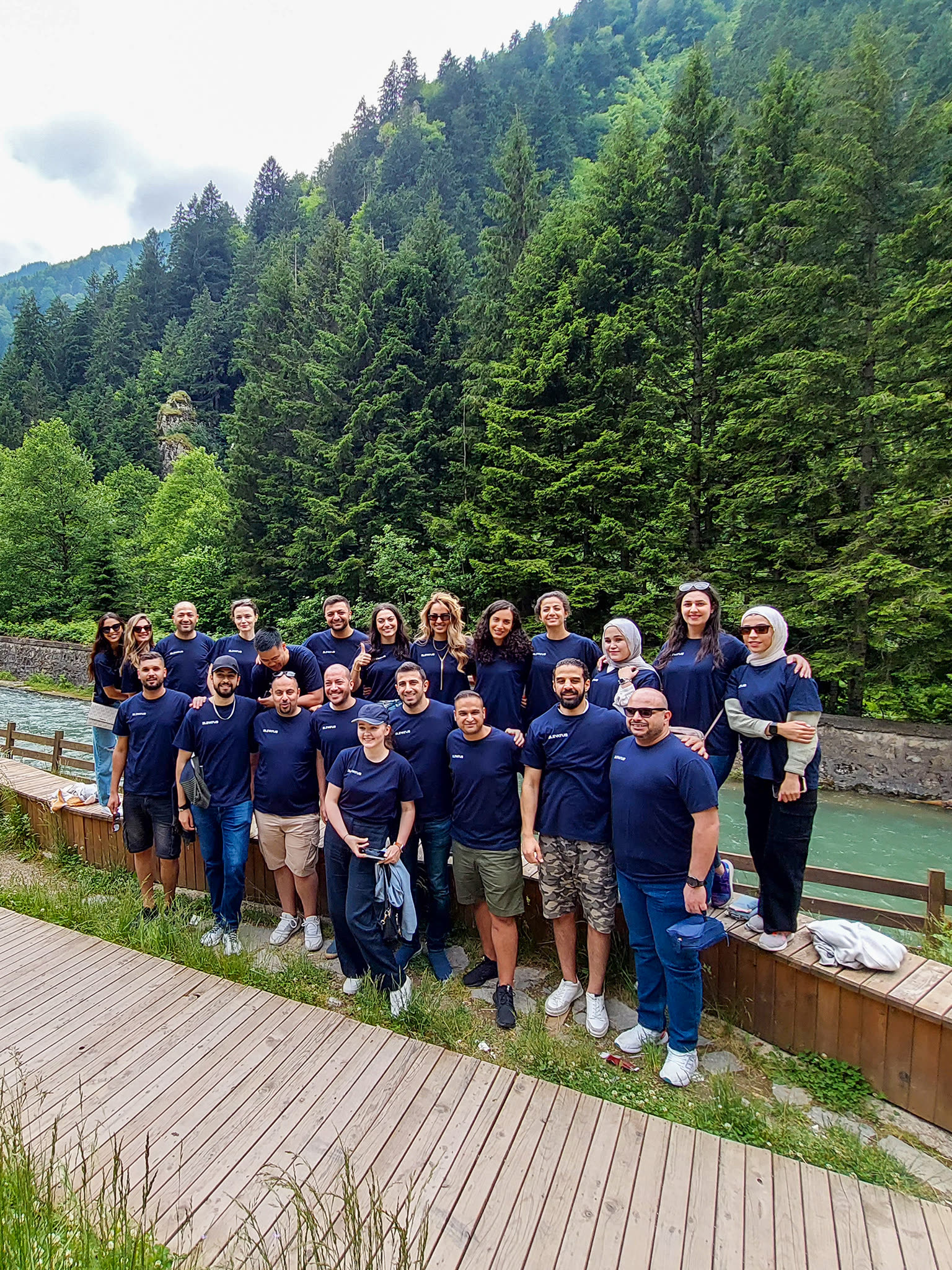 Elevatus team gathered together outdoors on a forest riverside walkway during a company retreat